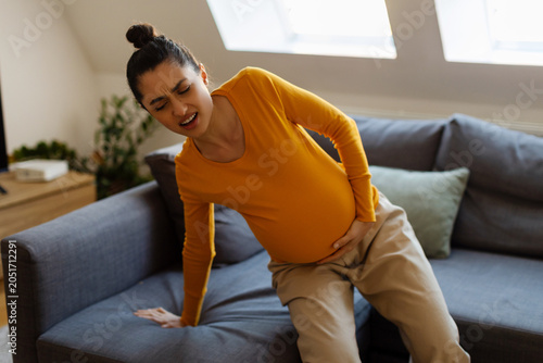 Canvas Print Expectant mother holding her abdomen while struggling with pregnancy discomfort