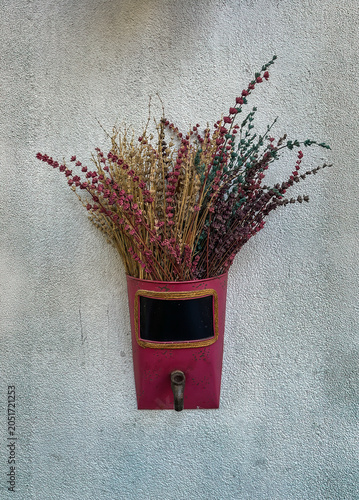 Istanbul, Turkey - July 21, 2024: Asian part of town. Outside wall decoration of dried stems, artificially dyed, set in a decorative wall planter made from an old metal watering can or grain scoop, re