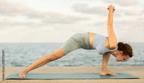 During street workout, yoga practice on embankment, female athlete fulfil carry out elongated side angle, Utthita Parshvakonasana