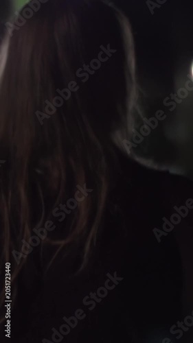 Vertical footage of back view of a young woman walking in desert poorly lighted street. She is scared to be alone outside at night