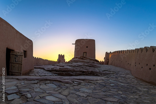 Interior courtyard of Zaabal Castle with ancient mud walls and watchtower at sunset in Sakaka