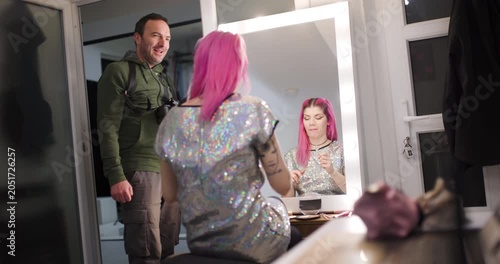 Model prepares for a shoot while interacting with stylist in a stylish studio setting at evening