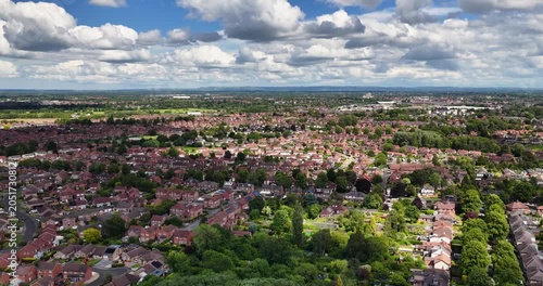 Aerial drone footage of the village of Acomb York North Yorkshire UK showing streets and rows of British residential housing estates beneath a dramatic cloud filled sky in the summer time