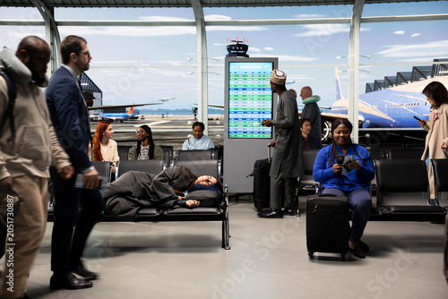 Schilderij op canvas Sleeping, jet lag and woman on airport bench next to people checking flight schedule screen, napping, city break and Tired tourist on chair in departure terminal traveling internationally