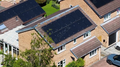 Aerial footage of a modern detached houses fitted with rooftop solar panels in a residential neighbourhood near Acomb York North Yorkshire highlighting renewable energy adoption and sustainable living