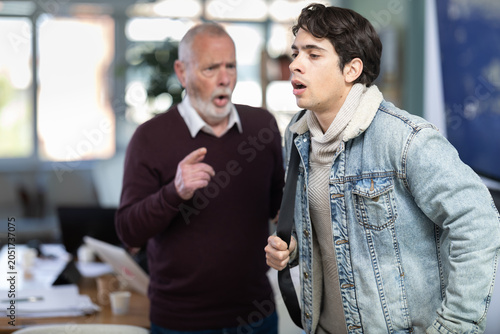 Fotografie Elderly man sternly scolds young male colleague for being late for work in offic