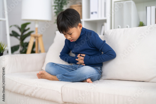 Bild auf Leinwand Portrait of sick unhappy little child asian boy touching belly stomach with suff