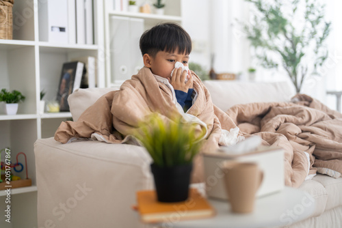 Foto Young asian boy sneezing or blowing his nose and mouth with tissue, cold allergi