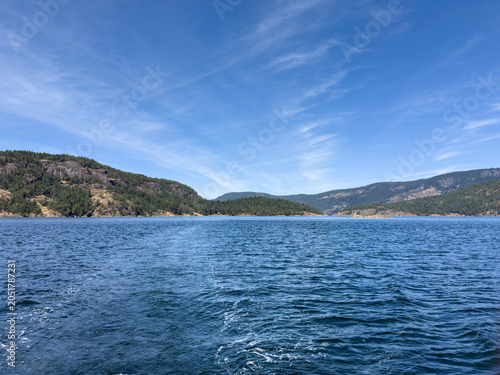 View across water of tree covered rugged mountains and sky