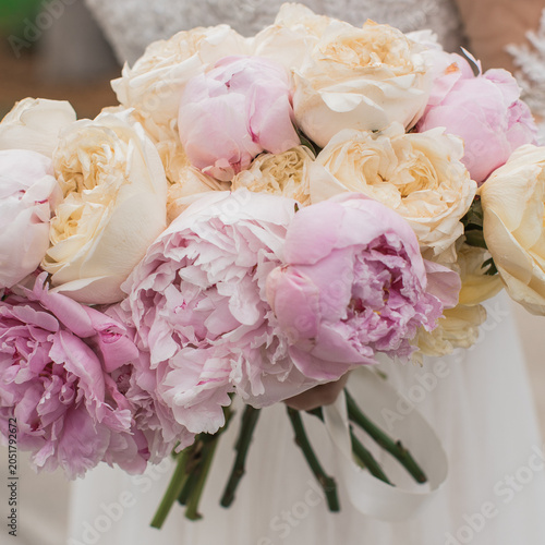 closeup of a bride holding a bouquet of white and pink peonies 