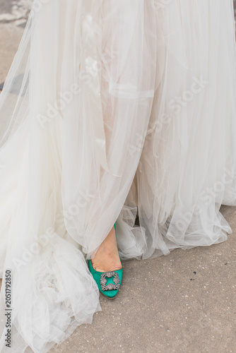 a bride in a white wedding dress with emerald green heels 