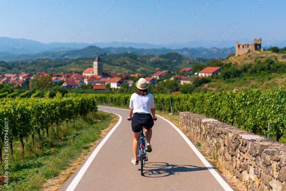 Obraz premium Cycling through vineyard landscape with woman on bicycle on summer vacation