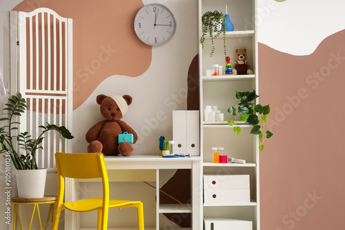Interior of pediatrician's office with workplace, shelf unit and folding screen