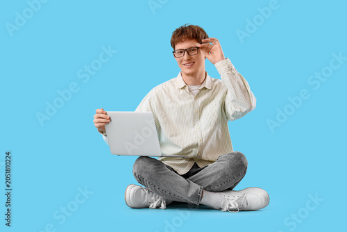 Young man with laptop sitti...