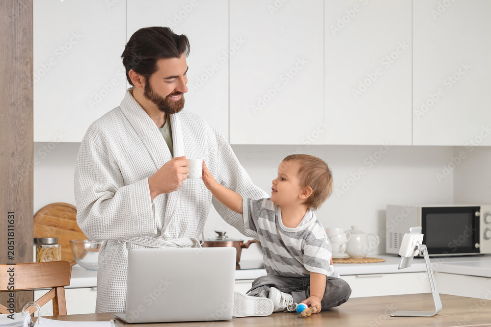 Obraz premium Working father with coffee and his little baby during parental leave in kitchen