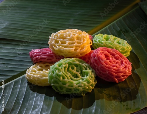 A visually stunning ultra-detailed studio composition featuring vibrant colorful traditional ring crackers arranged artistically upon fresh green banana leaves