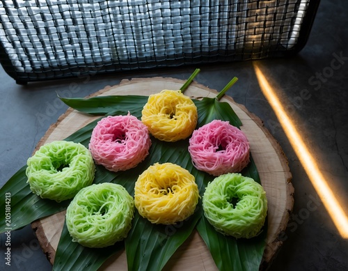 Vibrant, colorful traditional sweet desserts, meticulously arranged in delicate nests on fresh green banana leaves, beautifully captured in a detailed studio shot
