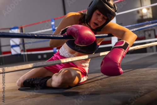 Φωτογραφία Pink boxing gloves are resting on middle ropes of blue and crimson ring at train