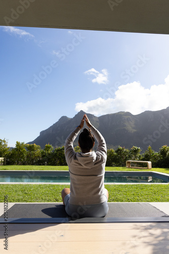 Yoga mat is resting on wooden patio beside rectangular pool, mountains rising beyond