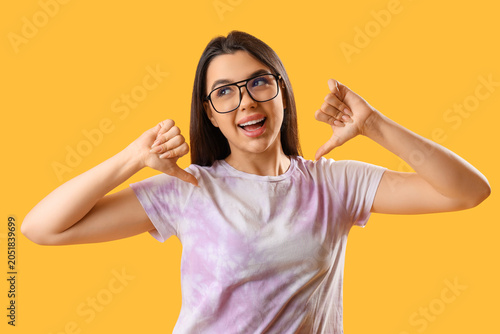 Obraz na płótnie Pretty young woman wearing glasses and showing thumb-down on yellow background
