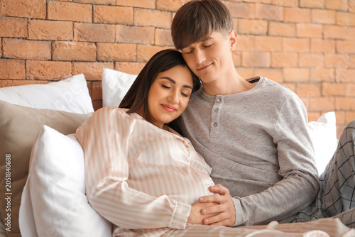 Young pregnant couple lying...