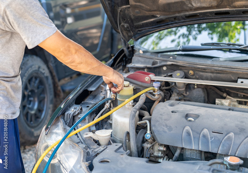 Bild auf Leinwand Auto mechanic connecting manifold gauge hoses to the air conditioning system valves under the hood of a car for diagnostics and refilling refrigerant