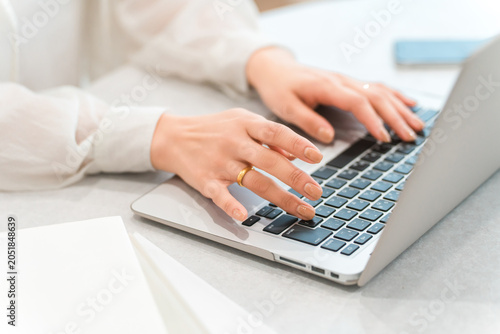 Obraz na plátně A woman's hands while using a laptop (typing, teleworking, side job, part-time w