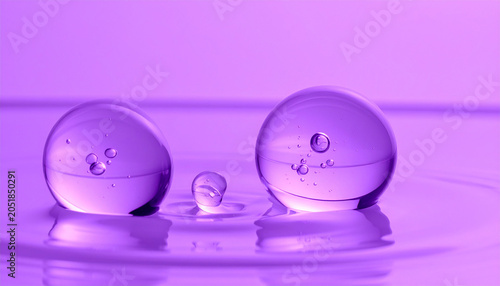 Purple Water Droplets: Abstract macro shot featuring three translucent purple water droplets in various sizes on a purple surface. Close-up view with reflections and small bubbles inside the drops.
