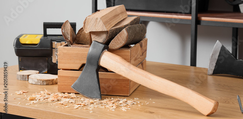 Fotografía Wood chopping axe with wooden handle and firewood in crate, wood shavings on tab