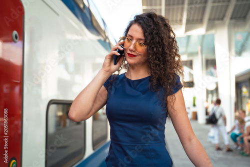 Closeup shot of beautiful curly hair young business woman talking on the phone and the train station