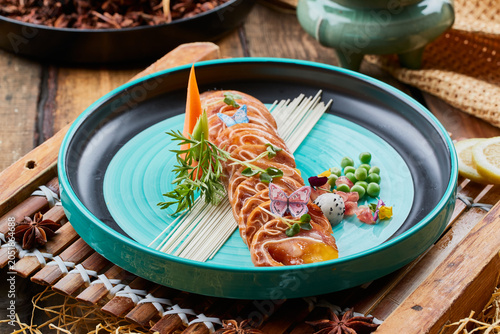 Фотография Flavored braised pig ear flowers on a two-tone round porcelain plate on an old w