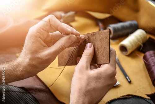 Foto Man with needle sewing leather in workshop