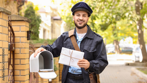 Handsome postman putting le...