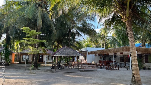 Cozy beachfront resort area with wooden gazebos restaurant and coconut palm trees