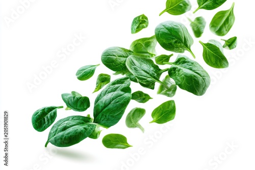 Fresh green spinach leaves scattered against a white background, highlighting their texture and vibrant color.