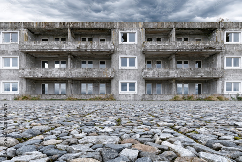 Obraz premium Abandoned concrete building with balconies and broken windows under a stormy, dramatic sky.