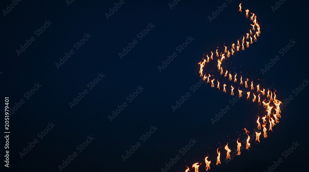 Obraz premium Group of People Carrying Torches in a Winding Line at Night Creating a Luminous Path
