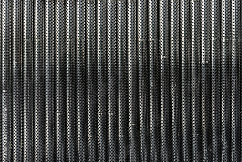 Repeating Texture of Industrial Perforated Steel Pipes. Parallel metallic tubes featuring a dense grid of circular perforations. For modern architectural or technology-themed backgrounds.