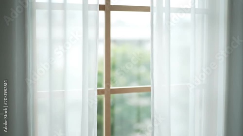 Soft white sheer curtains gently blowing in the breeze near a window.