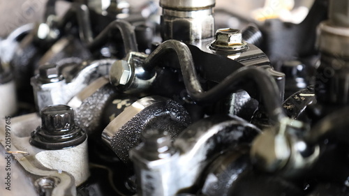 Combustion engine camshaft. Close-up of dirty camshaft on diesel engine cylinder head with black engine oil stains under repair in garage with selective focus.