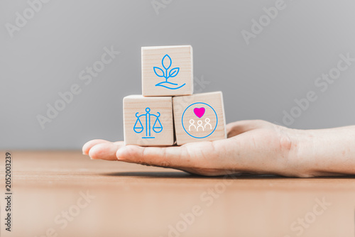 Hand Holding Wooden Blocks with Community Support Balance and Personal Growth Icons for Mental Wellbeing Concept