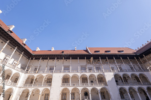 Historic building shows detailed arches and clear blue sky in a courtyard setting during daytime hours. Wawel castle, Kraków. Poland