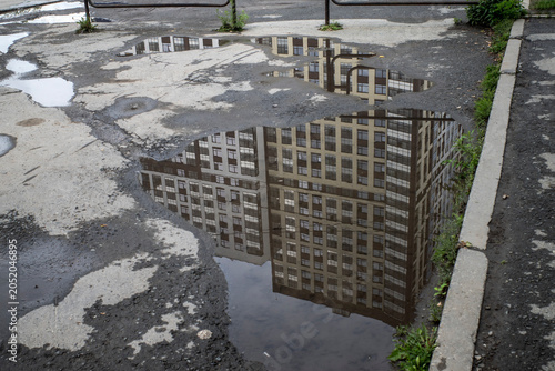 The building is reflected in a rain puddle on a summer day