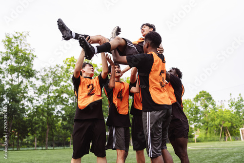 Картината върху платно Diverse soccer team lifting a teammate to celebrate victory on the field
