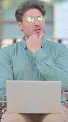 Middle Aged Man Thinking while using Laptop, Outdoor, vertical video