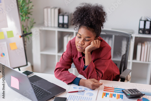 Foto Young professional woman sitting at her office desk, feeling exhausted and disen