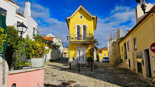 Принти на полотні Bright yellow house contrasting with white buildings along a traditional Portugu