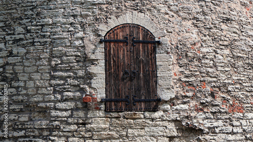 Fotografie Dark weathered wooden door with heavy iron hinges and rings set into rough stone
