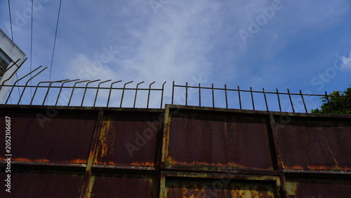 Blurred shadow of an iron gate tip on a closed iron gate, The composition emphasizes light, shadow, and selective focus, creating a moody and minimal industrial atmosphere