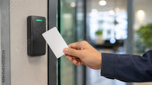 A person holding a key card to access a secured door in a modern office building.